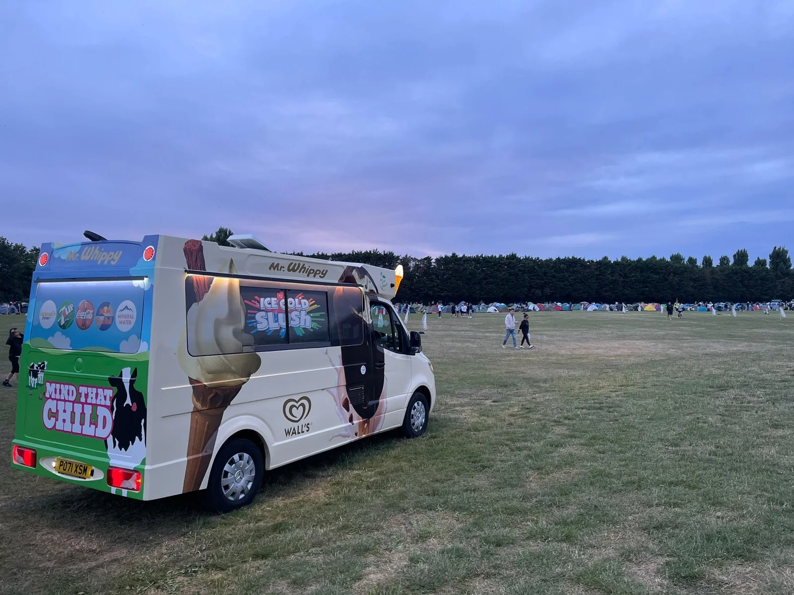 A Kreamy Delights electric ice cream van on a field at dusk