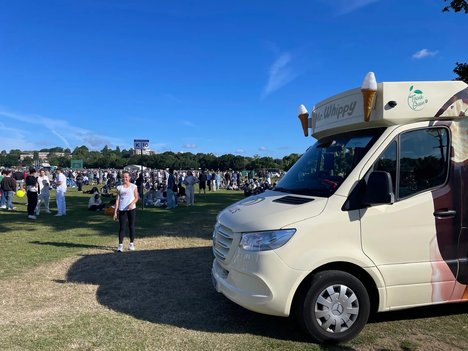 A Kreamy Delights van parked on the grass at a busy outdoor London event